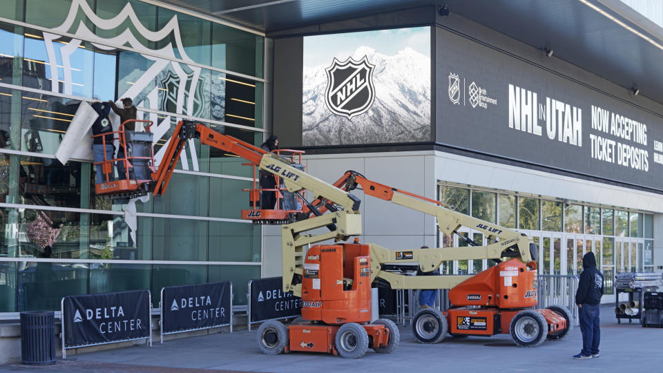 FILE - Workers put up signs celebrating the awarding of a new NHL team to Utah at the Delta Center Thursday, April 18, 2024, in Salt Lake City. It may look like an NHL team has just fallen into Salt Lake City's lap. But local organizers say the Arizona Coyotes' relocation to Utah is the product of a yearslong effort to beckon professional hockey and other elite sports to the capital city. (AP Photo/Rick Bowmer, File)