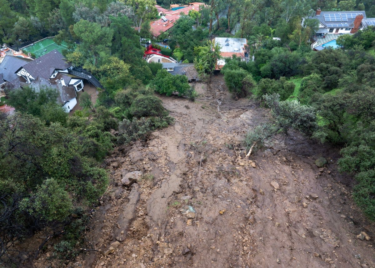 In an aerial view, a mudslide leads to a home where it smashed through its garage as a historic atmospheric river storm inundates the Studio City section of Los Angeles (AFP via Getty Images)