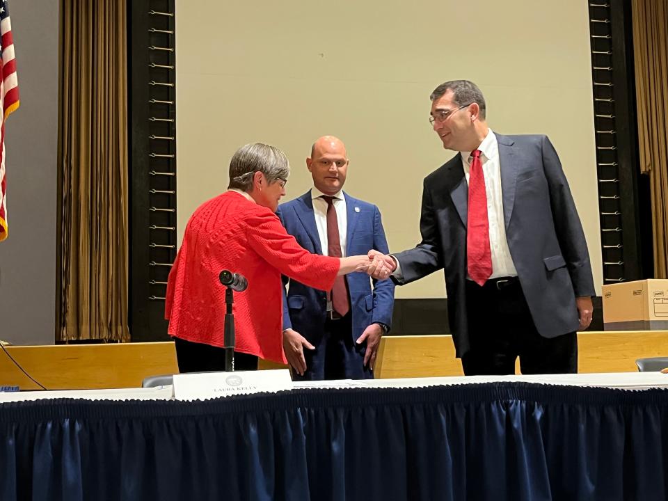 Gov. Laura Kelly and Attorney General Derek Schmidt shake hands in front of Secretary of State Scott Schwab at a Board of Canvassers meeting on Thursday in Topeka.