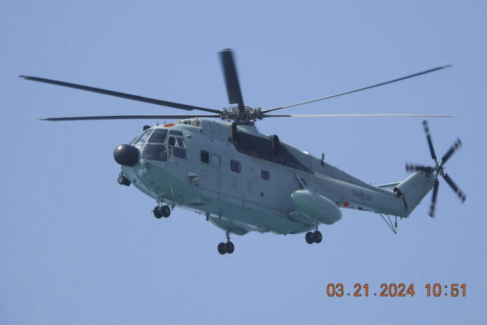 In this photo provided by the Philippine Coast Guard, a Chinese military helicopter flies near a Philippine government vessel as it approaches sandbars called Sandy Cay at the disputed South China Sea on Thursday March 21, 2024. Chinese coast guard ships, backed by a military helicopter, tried to dangerously block but failed to stop two Philippine government vessels carrying scientists from reaching two barren sandbars called Sandy Cay in the disputed South China Sea, Philippine officials said Friday. (Philippine Coast Guard via AP)