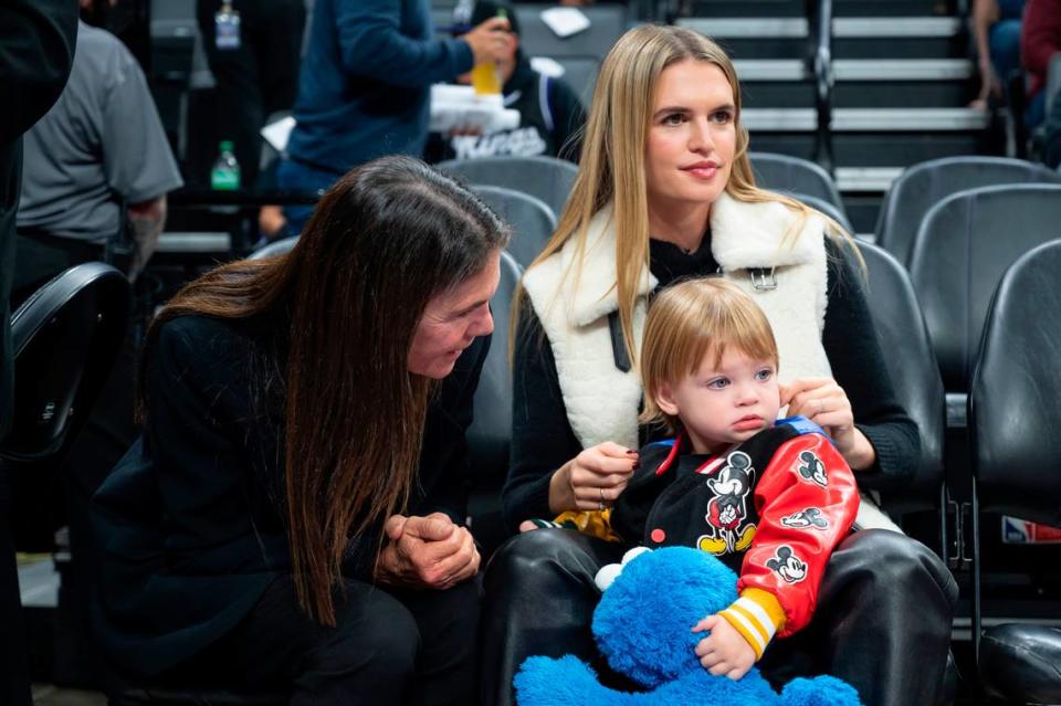 Shashana, right, holds her son Tiger, 1, as she watches her husband Sacramento Kings forward Domantas Sabonis (10) warmup and her mother Tiffany talks with Tiger before the NBA basketball game against the Minnesota Timberwolves on Saturday, Dec. 23, 2023, at Golden 1 Center. Sara Nevis/snevis@sacbee.com