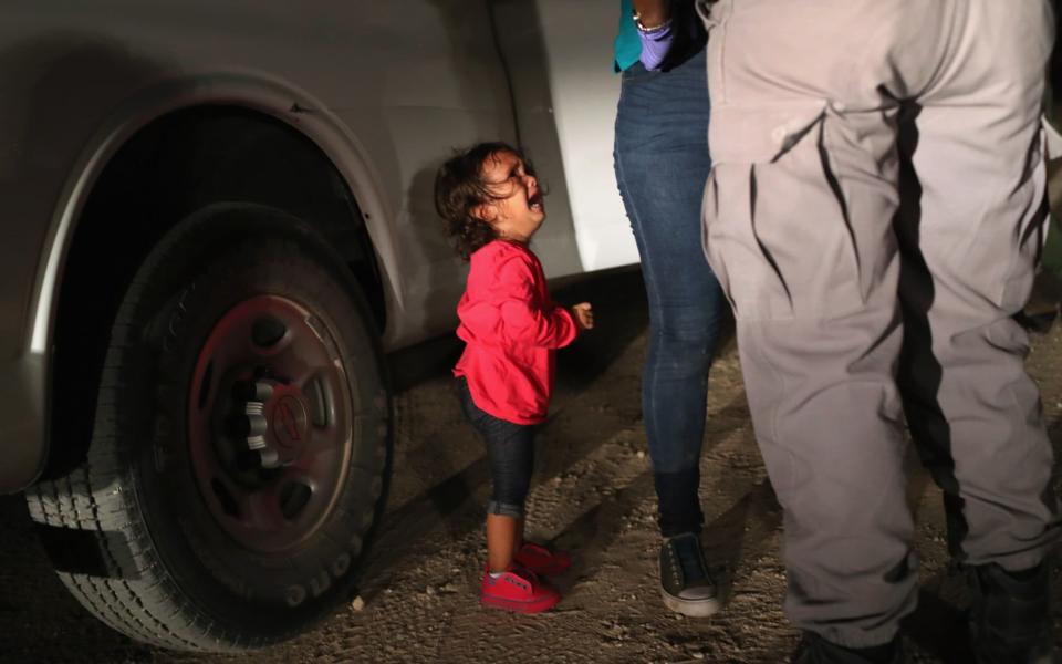 Yanela Varela Hernandez, aged two, weeps as her mother Sandra is patted down by border agents in Texas. She is currently with her mother at a shelter, her father said - Getty Images North America