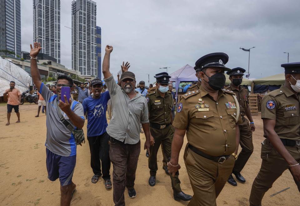 Protesters react to a police announcement aired using loudspeakers ordering protesters to vacate the site of months long anti government protests outside the president's office in Colombo, Sri Lanka, Thursday, Aug. 4, 2022. Sri Lanka's Parliament approved a state of emergency July 27. The decree gives the president the power to make regulations in the interest of public security and order. (AP Photo/Eranga Jayawardena)