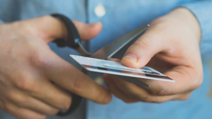 Man cutting credit card with scissors.