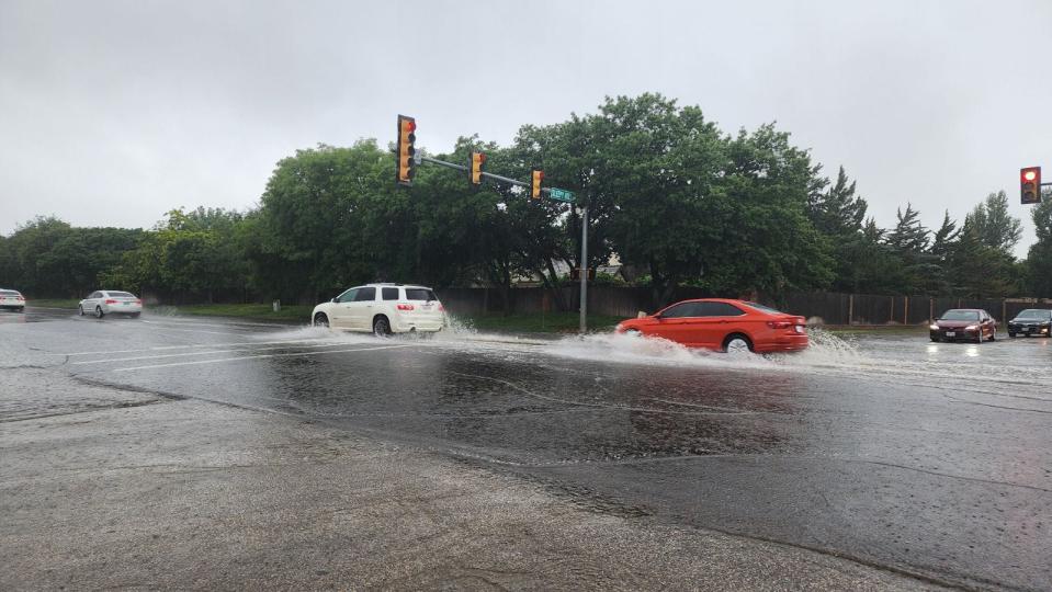 Vehicles drive through a flooded intersection at 34th and Coulter in Amarillo on Monday afternoon.