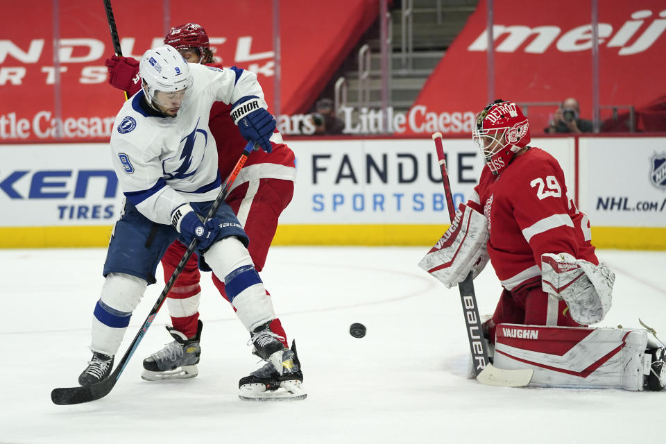 Tampa Bay Lightning center Tyler Johnson (9) redirects the puck towards Detroit Red Wings goaltender Thomas Greiss (29) as Marc Staal (18) defends the first period of an NHL hockey game Tuesday, March 9, 2021, in Detroit. (AP Photo/Paul Sancya)