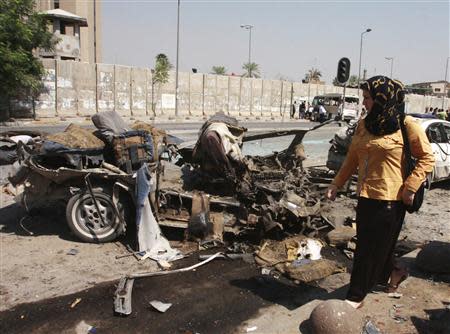 A woman walks past the site of a car bomb attack in Baghdad, September 18, 2013. REUTERS/Ahmed Malik