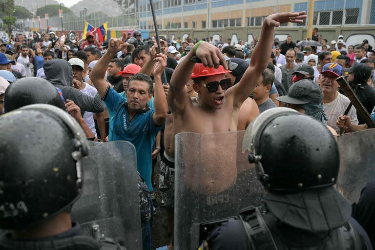 Manifestantes protestan frente a la policía en Caracas.