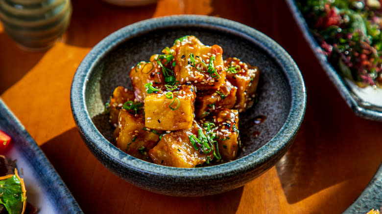 cubed tofu served in a bowl with sesame seeds and scallions