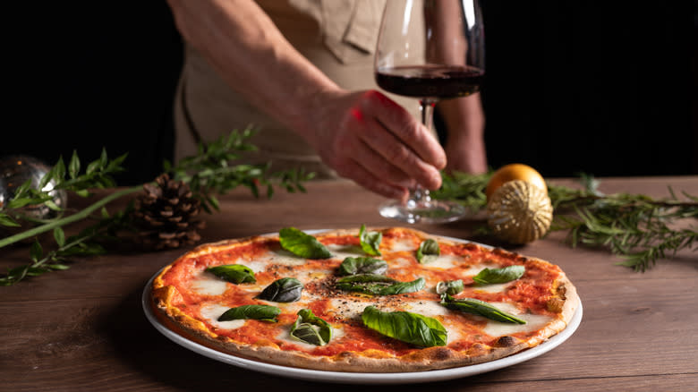 Margherita pizza on wood table with glass of red wine