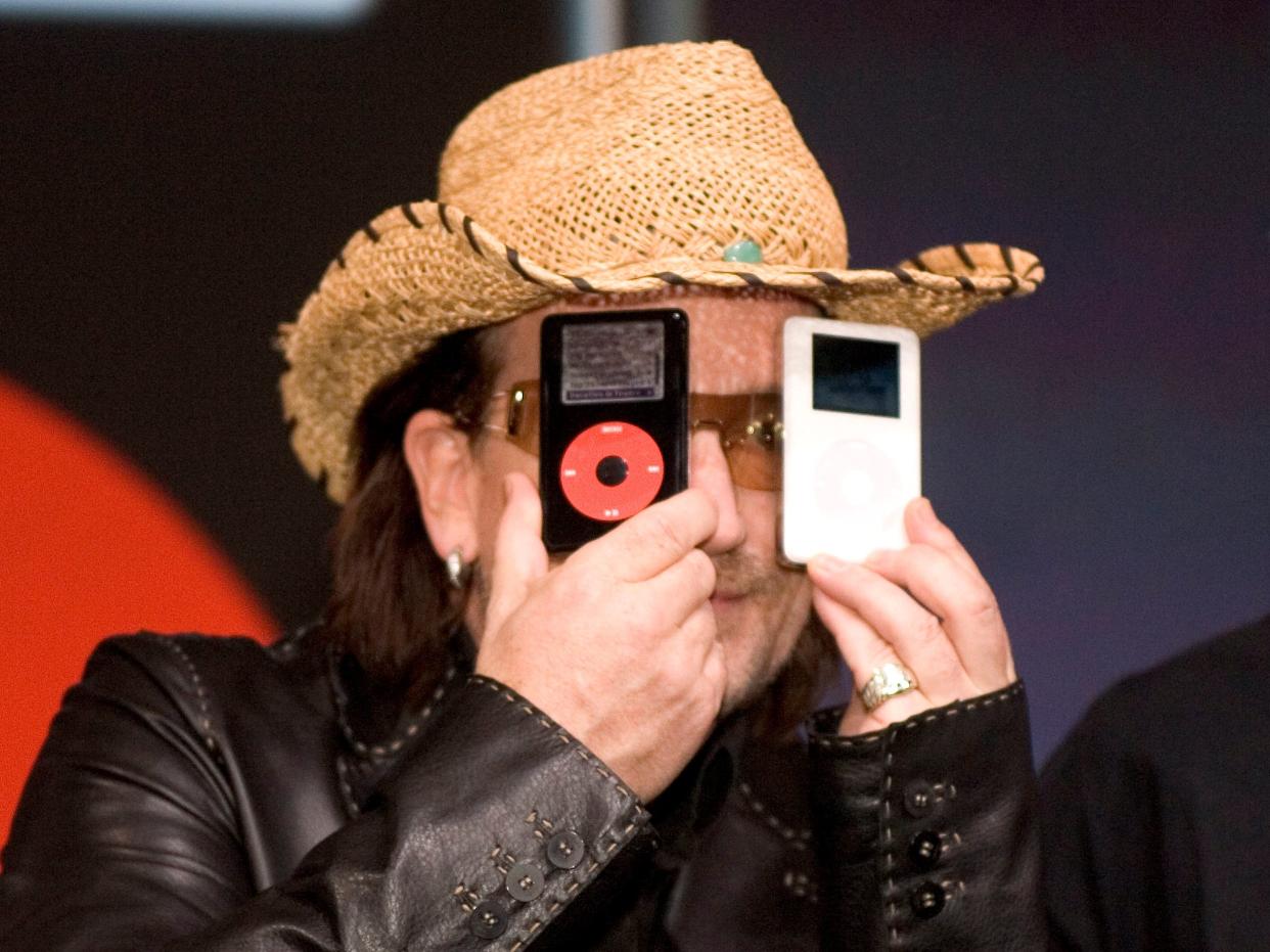 U2 band member Bono, left, holds a white iPod and a U2 Special Edition iPod as part of a partnership between Apple, U2 and Universal Music Group (UMG) as Apple CEO Steve Jobs looks on during a press conference in San Jose, California.