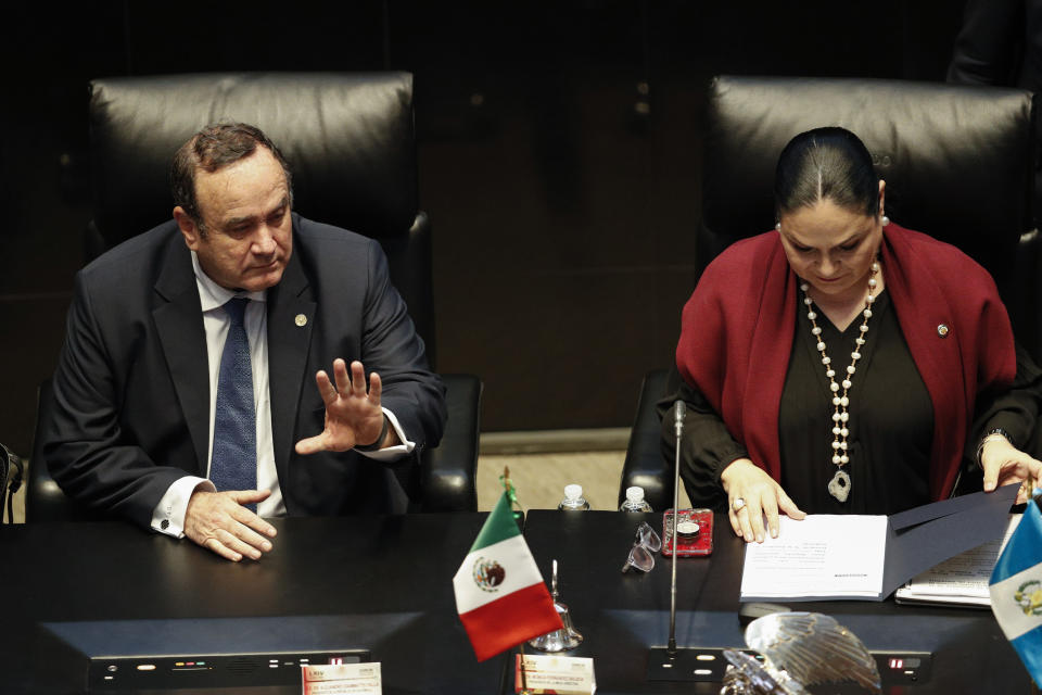 Guatemala's President Alejandro Giammattei waves as he takes a seat beside Mexican Senate President Monica Fernandez Balboa for the opening of a senate session in Mexico City, Thursday, Feb. 6, 2020. (AP Photo/Rebecca Blackwell)