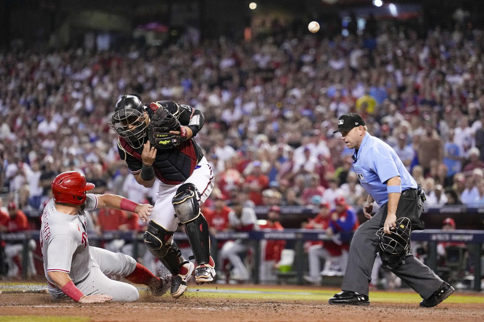 Philadelphia Phillies' Kyle Schwarber is safe at home past Arizona Diamondbacks catcher Gabriel Moreno on a hit by Alec Bohm during the sixth inning in Game 4 of the baseball NL Championship Series in Phoenix, Friday, Oct. 20, 2023. (AP Photo/Brynn Anderson)