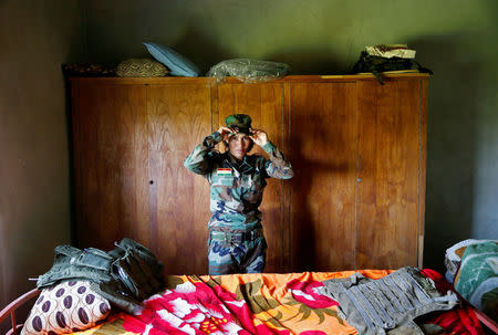 Yazidi female fighter Asema Dahir, 21, adjusts her cap inside a bedroom at a site near the frontline of the fight against Islamic State militants in Nawaran near Mosul, Iraq April 20, 2016. REUTERS/Ahmed Jadallah