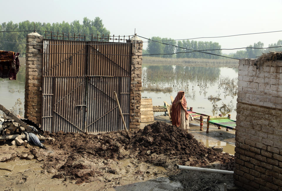 A woman walks near to damage home after heavy rains, in Charsadda, Pakistan, Wednesday, Aug. 31, 2022. Officials in Pakistan raised concerns Wednesday over the spread of waterborne diseases among thousands of flood victims as flood waters from powerful monsoon rains began to recede in many parts of the country. (AP Photo/Mohammad Sajjad)