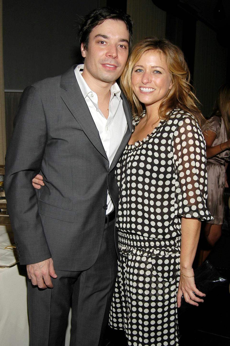 Jimmy Fallon in a gray suit with a white shirt, standing next to Nancy Juvonen in a polka-dot dress at an event