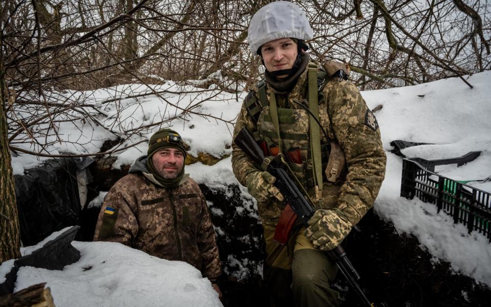 Ukrainian officer Vladyslav Kivish (right) and Oleksandr Sheva stand amid snow-covered trenches along the frontline in the southern Donbas area of Druzhba - Scott Peterson/Getty Images Europe