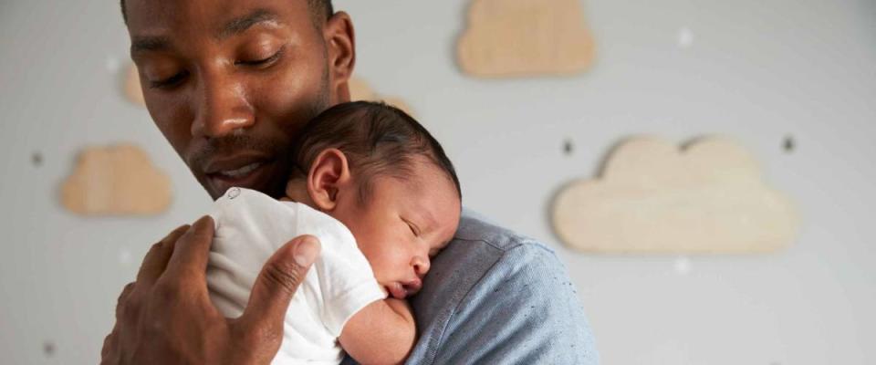 Father Holding Newborn Baby In Nursery