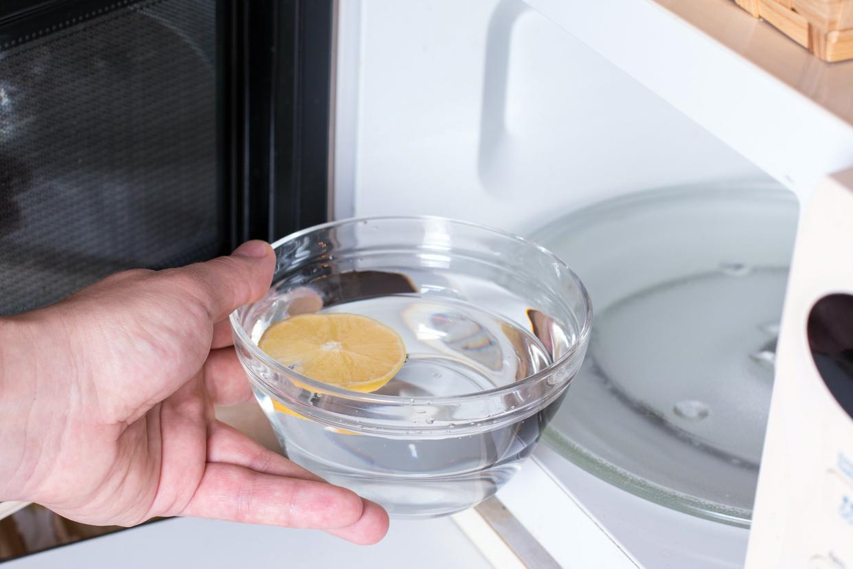 cleaning the microwave oven with water and lemon in a bowl