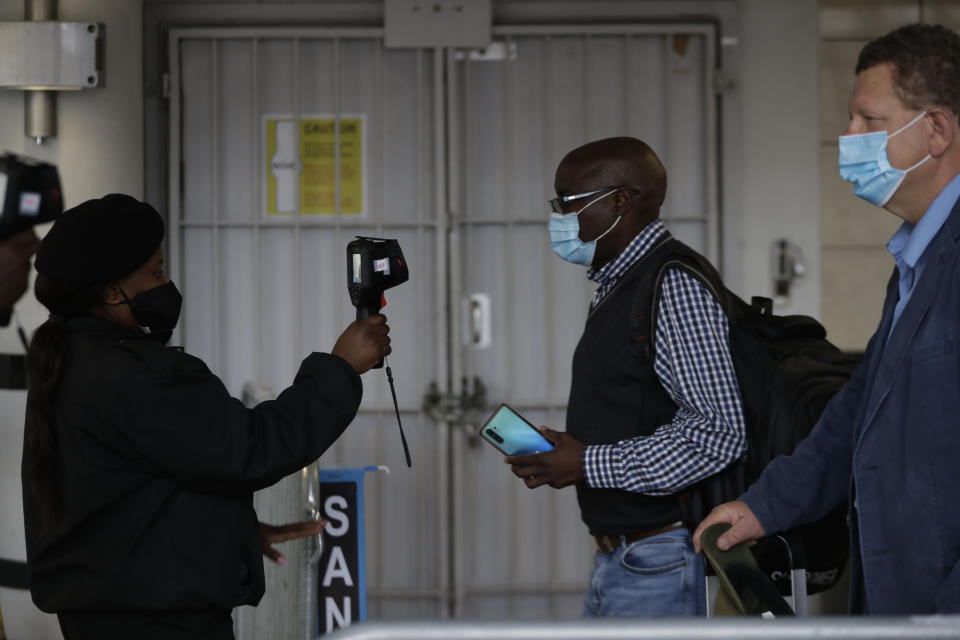 FILE — In this Thursday, Oct. 1, 2020 file photo passengers have their temperatures taken at the International O.R. Tambo Airport in Johannesburg, South African Health Minister, Zwerli Mkhize announced Monday, Oct. 19 2020 that he and his wife have tested positive for COVID-19, warning of a possible resurgence of the disease in the country. (AP Photo/Themba Hadebe/File)