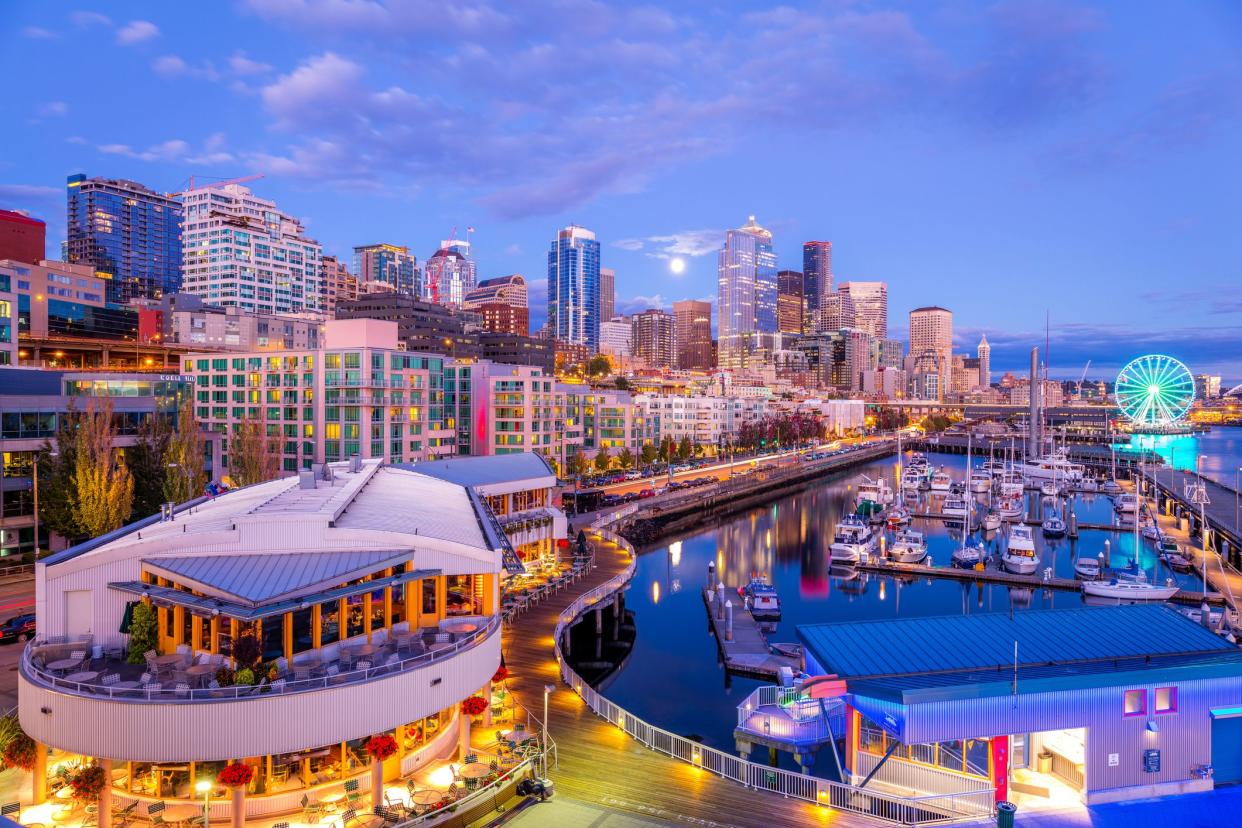 Early evening downtown Seattle, Washington Pier 66, full moon rising in the distance, pier shops and resturants brightly lit