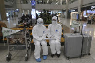 Chonnam National University staff wearing protective attire are on standby for special transportation for Chinese students studying at their university, at Incheon International Airport in Incheon, South Korea, Tuesday, Feb. 25, 2020. Chinese students of the university are to arrive from China after their holiday. China and South Korea on Tuesday reported more cases of a new viral illness that has been concentrated in North Asia but is causing global worry as clusters grow in the Middle East and Europe. (AP Photo/Ahn Young-joon)