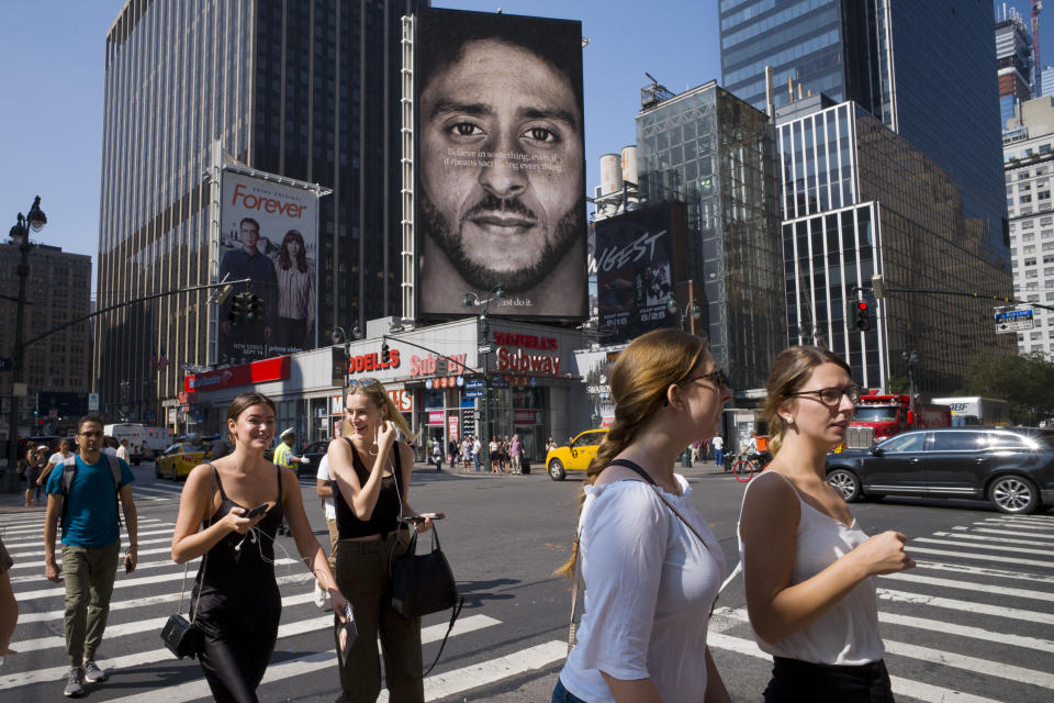 FILE - In this Sept. 6, 2018 file photo, people walk by a Nike advertisement featuring Colin Kaepernick in New York. In his &quot;Just Do It&quot; spot for Nike that marked the campaign's 30th anniversary in September, the sidelined-by-kneeling NFL quarterback somberly challenged viewers to &quot;believe in something, even if it means sacrificing everything.&quot; Some responded with anger, cutting or burning Nike gear and calling for boycotts. President Donald Trump slammed the company's move, while LeBron James defended it, saying he stands for those who believe in change. (AP Photo/Mark Lennihan, File)