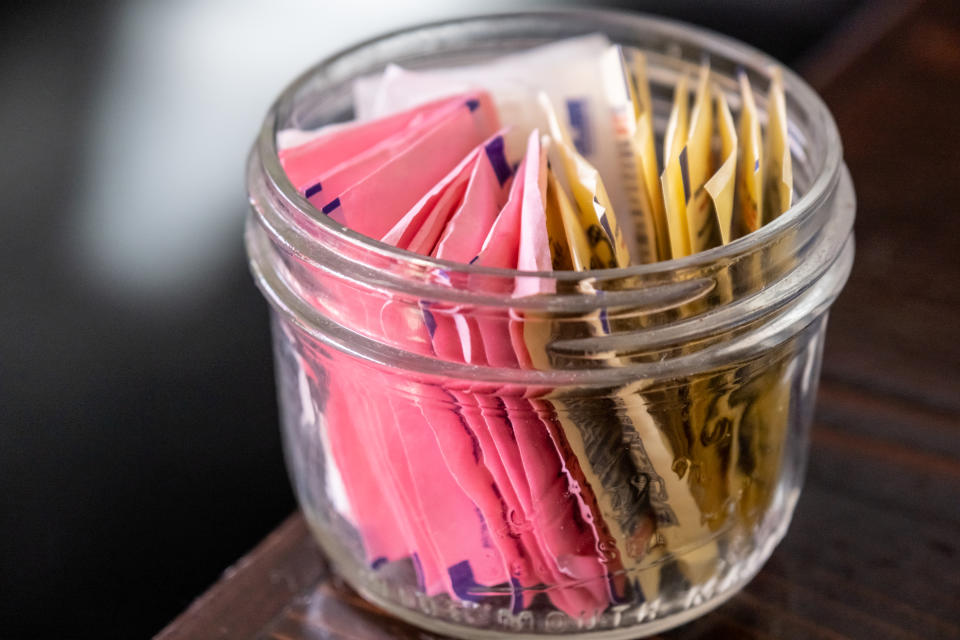 small glass bowl full of assorted artificial sweetener envelopes