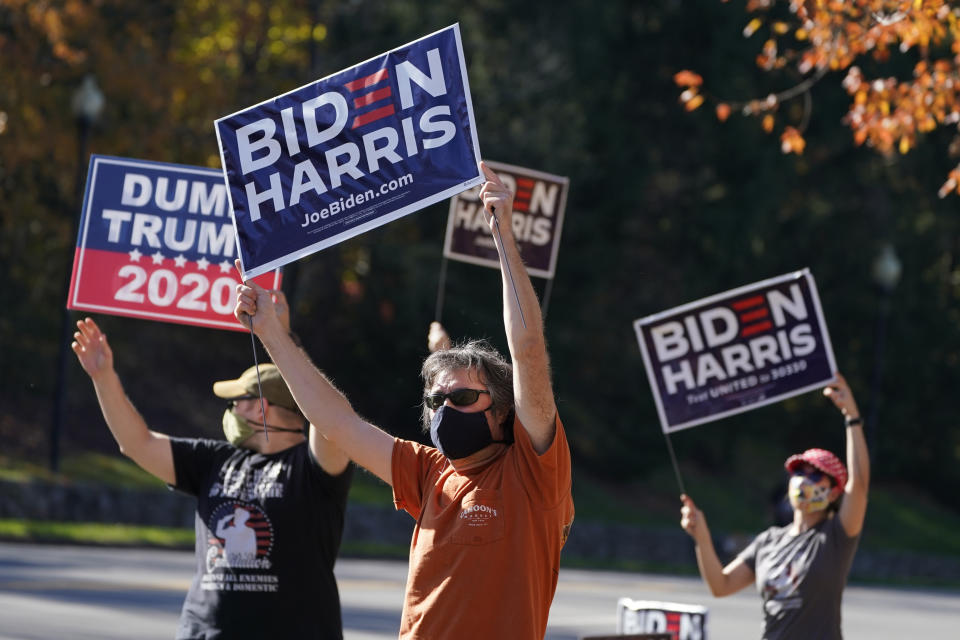 Supporters of President-elect Joe Biden wave signs at the entrance to Trump National golf club in Sterling, Va., Saturday Nov 7, 2020. Trump was at the facility. (AP Photo/Steve Helber)