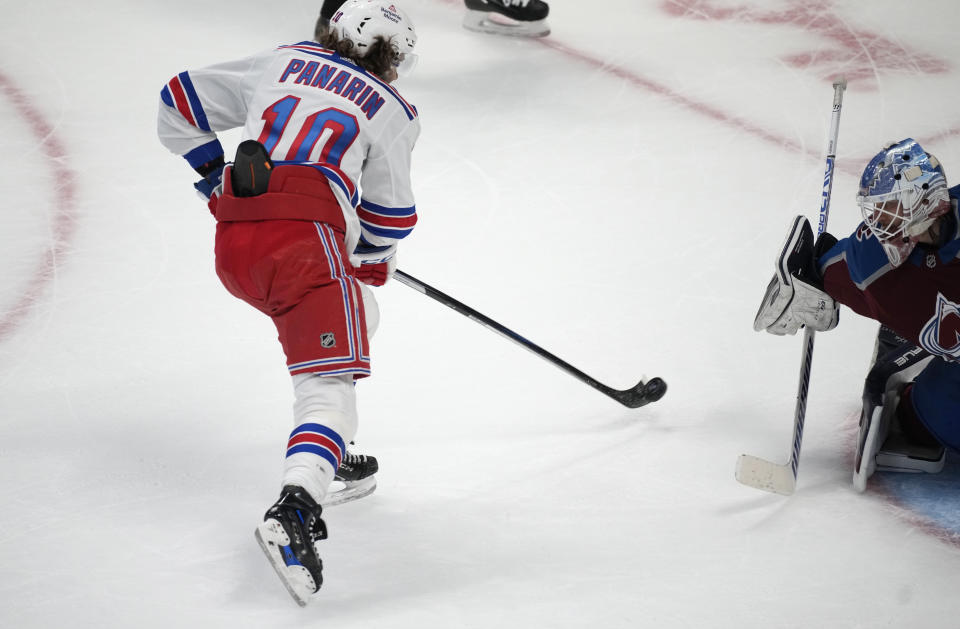 New York Rangers left wing Artemi Panarin, left, shoots past past Colorado Avalanche goaltender Alexandar Georgiev during the shootout of an NHL hockey game Friday, Dec. 9, 2022, in Denver. (AP Photo/David Zalubowski)