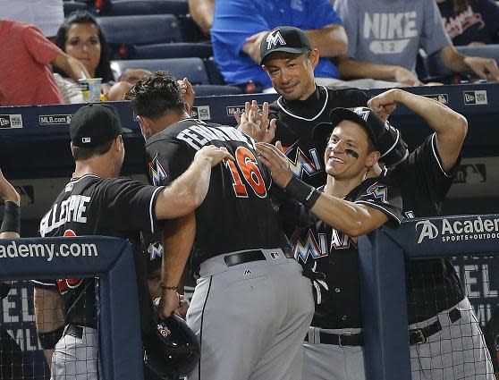 Jose Fernandez is mobbed at the dugout entrance after driving home the go-ahead runs in Friday's game against the Braves. (AP)