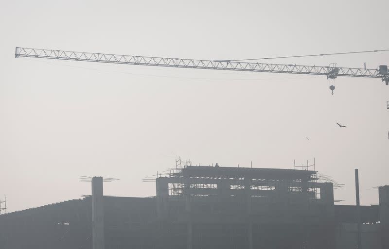 A labourer sits on top of an under-construction building on a smoggy morning in New Delhi