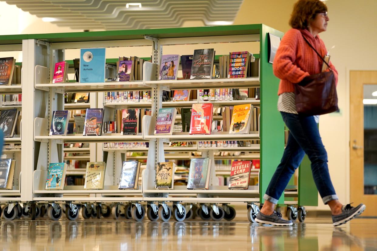 A reader passes by bookshelves at the Deer Park branch of Cincinnati and Hamilton County Public Library. Millions of materials are borrowed from the Public Library's 41 branches each year.