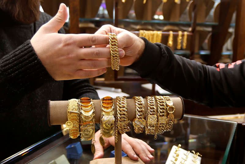 A salesman handles gold bracelet to a customer inside a jewellery shop in Beirut