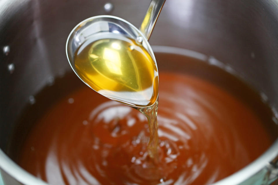 Ladling chicken broth into a pot