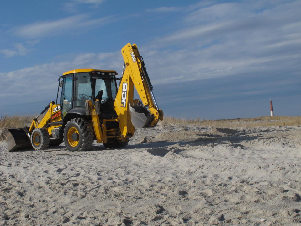 A front-end loader rests on the sand in Barnegat Light N.J. on Monday, Dec. 28, 2020, after burying a 15-ton humpback whale whose carcass had washed ashore three days earlier. (AP Photo/Wayne Parry)