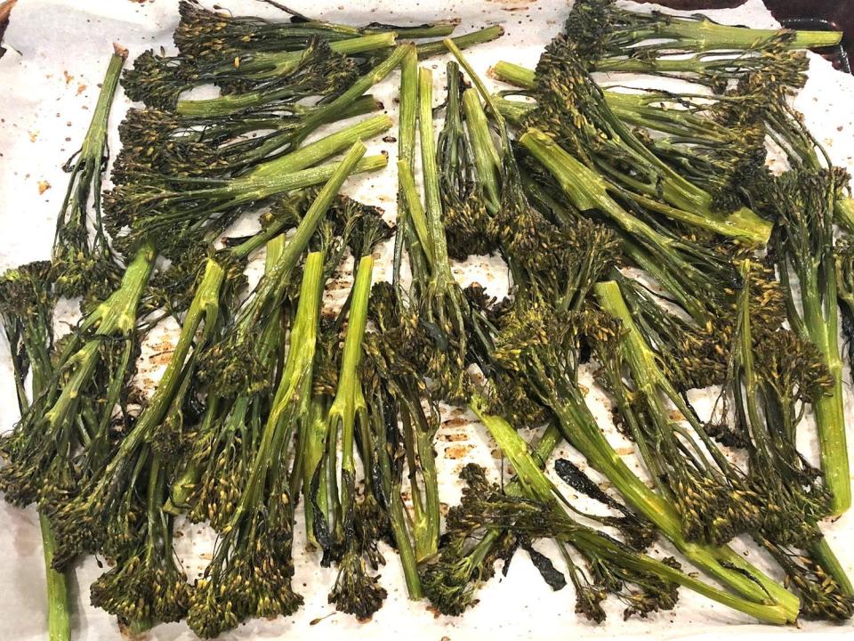 Seasoned Broccolini on a baking sheet with parchment paper