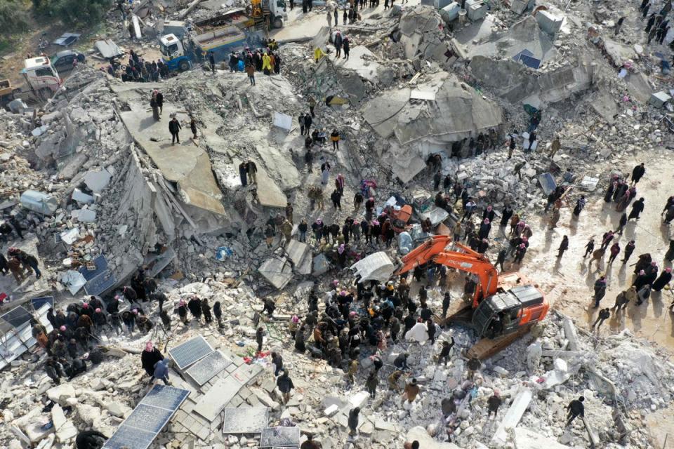 Residents aided by heavy equipment search for victims and survivors amidst the rubble of collapsed buildings in the Syrian village of Besnia (AFP via Getty Images)
