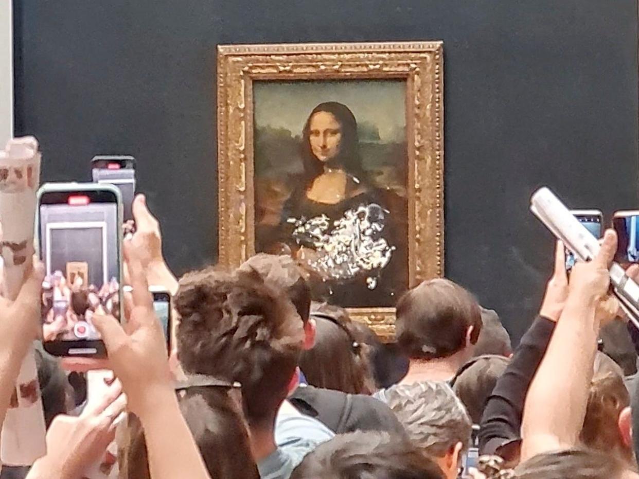 Visitors take pictures and video of the painting "Mona Lisa" after cake was smeared on the protective glass at the Lourve Museum in Paris, France May 29, 2022.