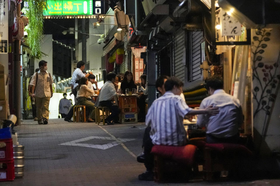 FILE - In this Sept. 22, 2021, file photo, people gather at bars that are open and serving alcohol on an ally filled with bars and restaurants despite Tokyo government has requested businesses not to serve alcohol under a state of emergency, in Tokyo. People in Tokyo could eat and drink inside bars and restaurants for longer evening hours starting Monday, Oct. 25, 2021 as officials eased social distancing rules with the country’s daily coronavirus cases reaching its lowest levels in more than a year. (AP Photo/Kiichiro Sato, File)