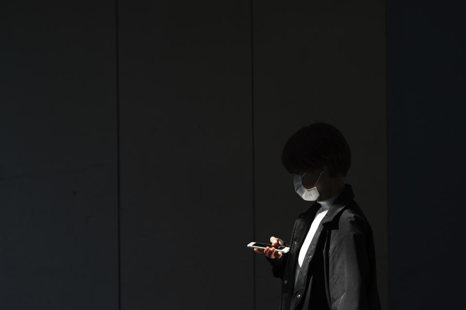 A woman with a protective face mask walks into the shade of an underpass Monday, April 6, 2020, in Tokyo. The new coronavirus causes mild or moderate symptoms for most people, but for some, especially older adults and people with existing health problems, it can cause more severe illness or death. (AP Photo/Eugene Hoshiko)