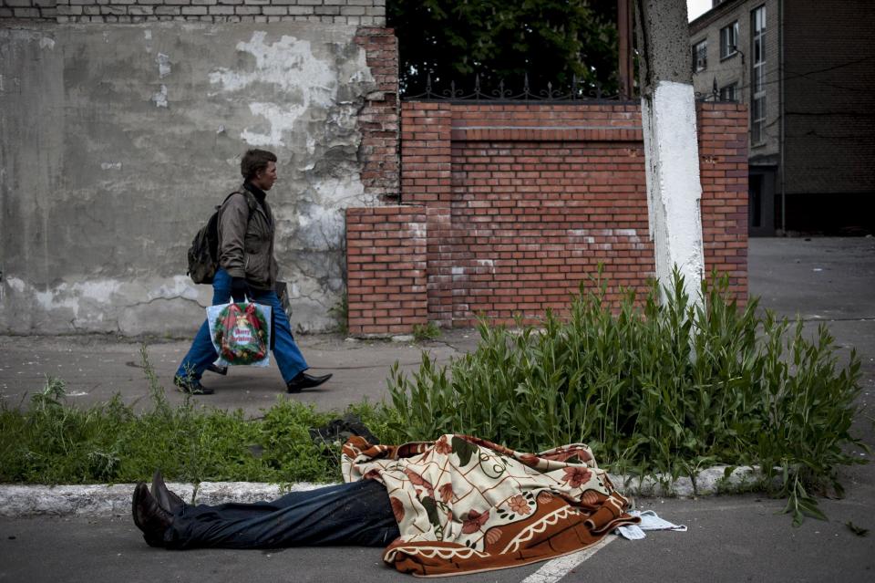 The body of a police officer lies outside a police station in Mariupol, eastern Ukraine, Friday, May 9, 2014. Fighting between government forces and insurgents in Mariupol has left several people dead. (AP Photo/Evgeniy Maloletka)