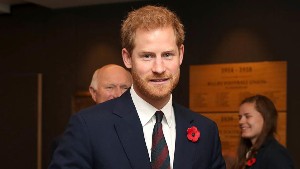 Prince Harry wearing a navy suit with a poppy
