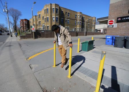 Honduran migrant Raul Contreras, who is seeking refugee status in Canada, balances on poles outside a bus station in Toronto, Ontario, Canada April 8, 2017. Picture taken April 8, 2017. REUTERS/Chris Helgren