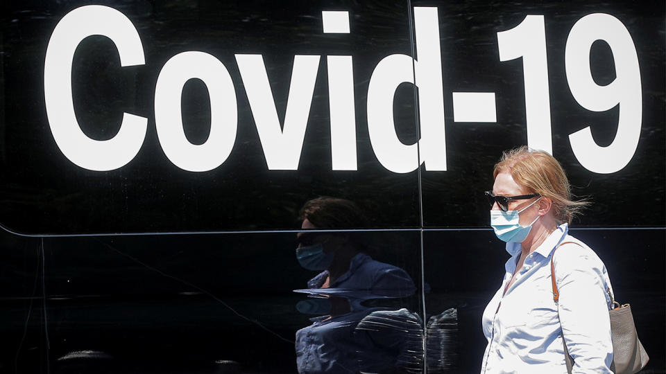 A woman wearing a mask passes by a coronavirus disease mobile testing van, as cases of the infectious Delta variant of COVID-19 continue to rise, in Washington Square Park in New York City in July.