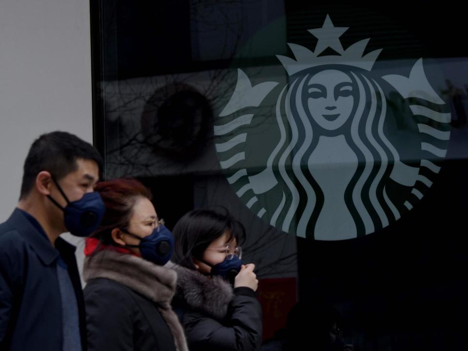 People wearing protective face masks walk past a closed Starbucks coffee shop in Beijing, China: Noel Celis/AFP/Getty