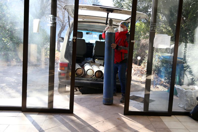 Miralem Sabic carries oxygen bottles from his private van to an improvised coronavirus disease (COVID-19) hospital in Konjic, Bosnia and Herzegovina