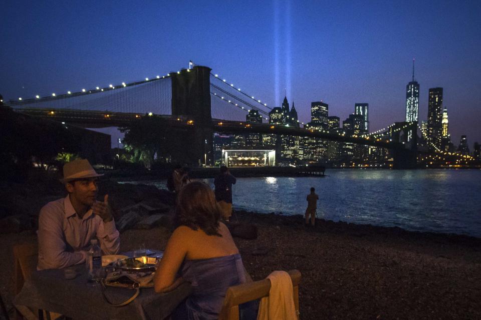 A couple enjoys dinner over looking the Brooklyn Bridge as the Tribute in Light illuminates the sky over the Lower Manhattan skyline a day ahead of the 12-year anniversary of the 9/11 attacks in the Brooklyn borough of New York on September 10, 2013. (REUTERS/Adrees Latif)