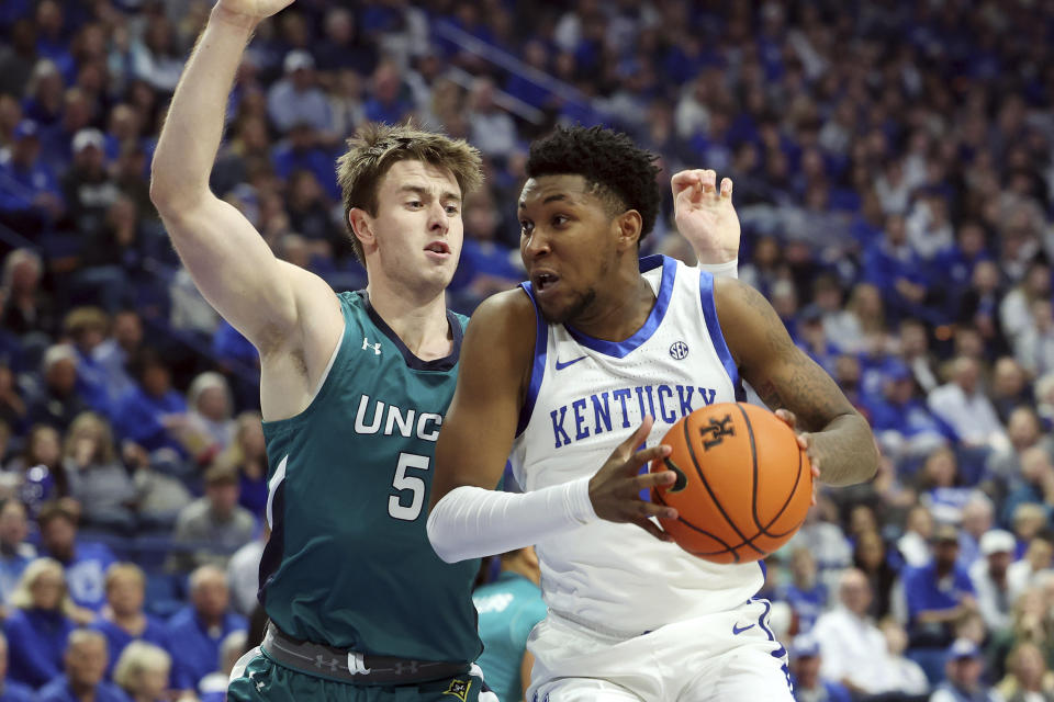 Kentucky's Justin Edwards, right, looks for an opening against UNC Wilmington's Noah Ross (5) during the first half of an NCAA college basketball game in Lexington, Ky., Saturday, Dec. 2, 2023. (AP Photo/James Crisp)