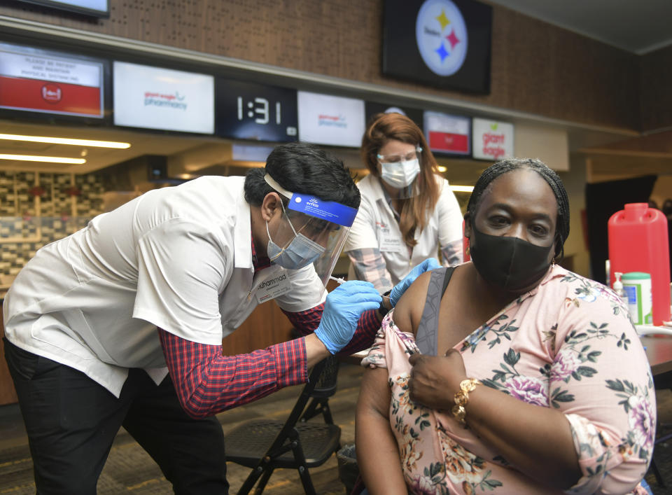 Dena Langston, a Pre-K teacher at the Pittsburgh suburb's Homewood-Brushton YWCA, receives a COVID vaccination from Muhammad Cheema, a pharmacist with Giant Eagle supermarket chain, Thursday, March 11, 2021, at Heinz Field in Pittsburgh. Giant Eagle Pharmacy partnered with the Pittsburgh Public Schools (PPS) to conduct a two-day COVID-19 vaccine clinic at Heinz Field. (Nate Guidry/Pittsburgh Post-Gazette via AP)